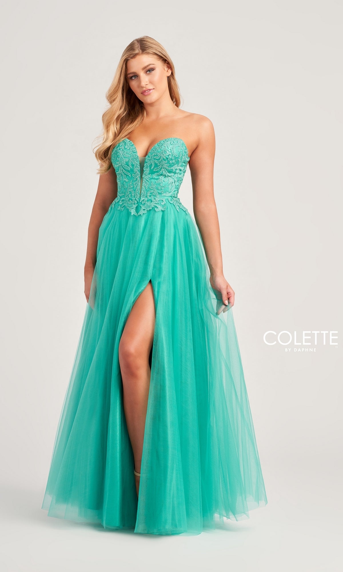 A woman poses against a plain background in the Colette Strapless Long A-Line Prom Dress CL5132, featuring a turquoise lace bodice, tulle skirt, and high leg slit.